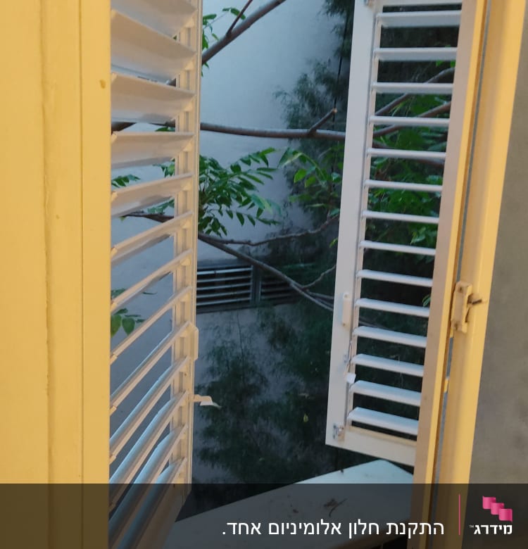 תריסי אלומיניום פתוחים ליד חלון